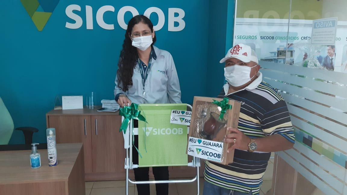 RADIALISTA JOÃO TEIXEIRA RECEBE DAS MÃOS DA GERENTE DO SICOOB AMAZÔNIA BRINDES QUE GANHOU DURANTE ASSEMBLEIA